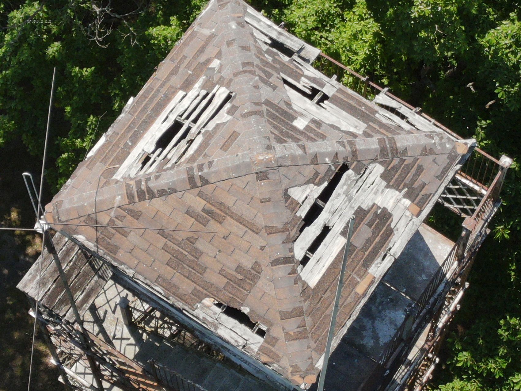Aerial photo of a lookout tower's pyramidal shingled roof showing deteriorated and displaced covering